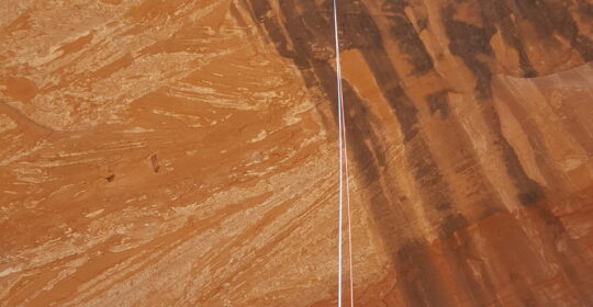 A climber rappelling off the top of looking glass arch in Moab Utah