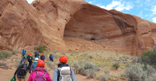 A group of climbers hiking towards Looking Glass Arch and the rope swing in Moab Utah