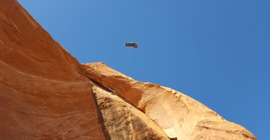 A climber on the rope swing on Looking Glass Rock in Moab Utah
