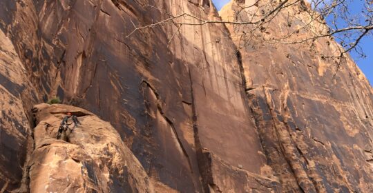A rock climber scaling the cliffs on Wall Street in Moab Utah