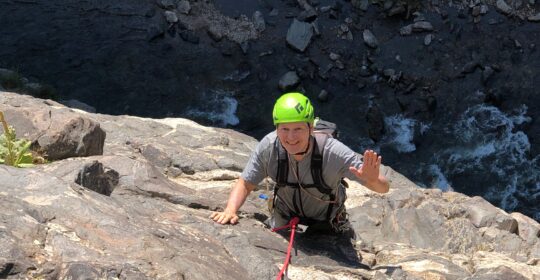 A rock climber waving hello on Playin' Hooky in Golden Colorado