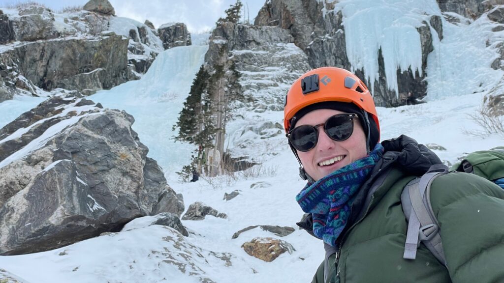 An ice climber smiling at the base of Lincoln Falls in Colorado