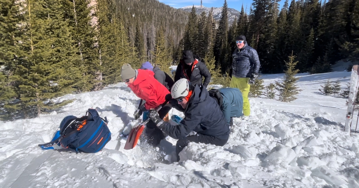 Students digging for a buried avalanche beacon on a pro 1 prep course